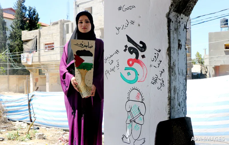 Artist Saja Moussa draws on broken tiles from her family's house in Rafah refugee camp, southern Gaza Strip, on June 16, 2021. The house was damaged last month during an 11-day war between Israel and the Hamas militant g...