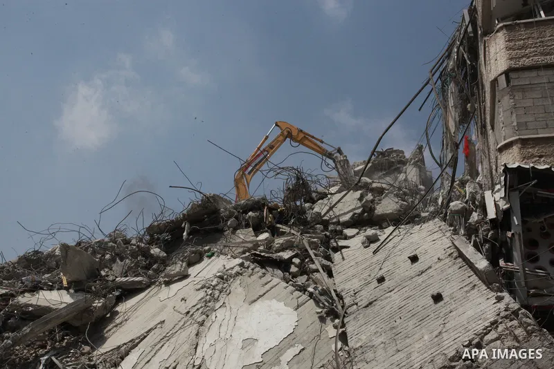 Egyptian workers and bulldozers sent from Egypt help to remove the rubble of Shorouq tower destroyed by Israeli air strikes last month in Gaza City on June 10, 2021. After brokering a ceasefire between the Israelis and H...