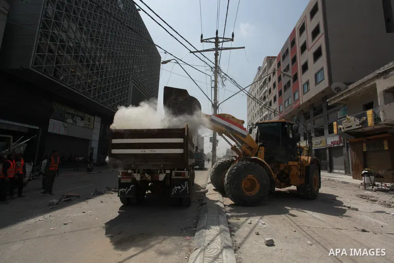 Egyptian workers and bulldozers sent from Egypt help to remove the rubble of Shorouq tower destroyed by Israeli air strikes last month in Gaza City on June 10, 2021. After brokering a ceasefire between the Israelis and H...