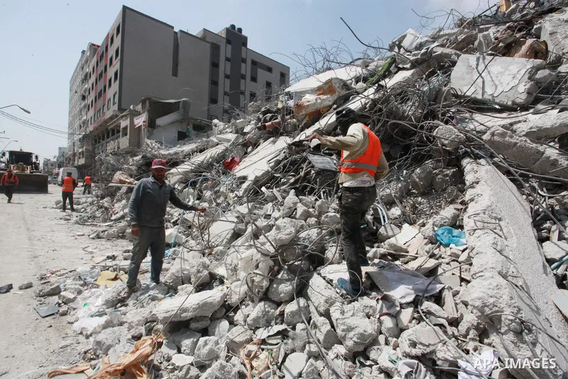 Egyptian workers and bulldozers sent from Egypt help to remove the rubble of Shorouq tower destroyed by Israeli air strikes last month in Gaza City on June 10, 2021. After brokering a ceasefire between the Israelis and H...