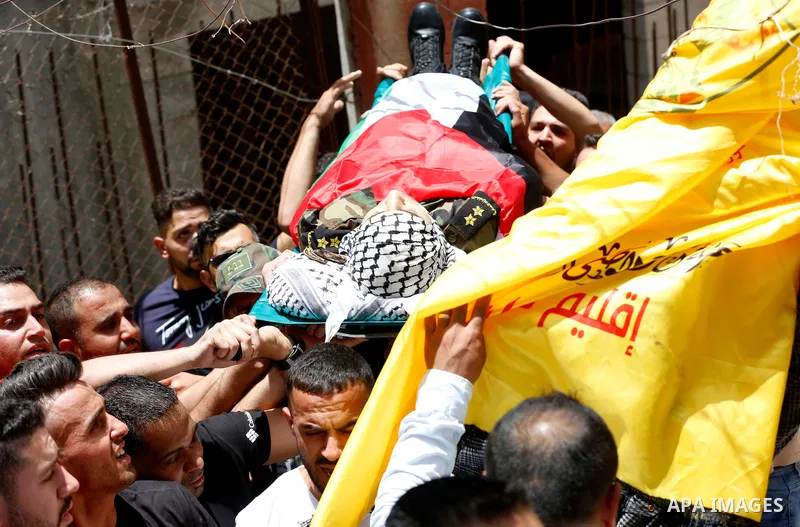 Members of Palestinian security forces carry the body of their comrade Adham Alioh, who was killed by Israeli forces according to health ministry, during his funeral in the West Bank city of Nablus on June 10, 2021. Phot...