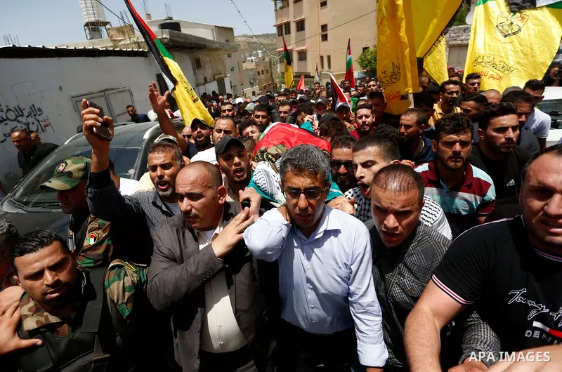 Members of Palestinian security forces carry the body of their comrade Adham Alioh, who was killed by Israeli forces according to health ministry, during his funeral in the West Bank city of Nablus on June 10, 2021. Phot...
