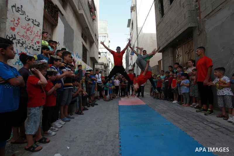 Palestinian volunteers perform acrobatic show in front of children during a mental health support session in Gaza city on June 9, 2021. As Gaza tries to recover from the deadly 11-day Israeli attack, mothers and mental h...
