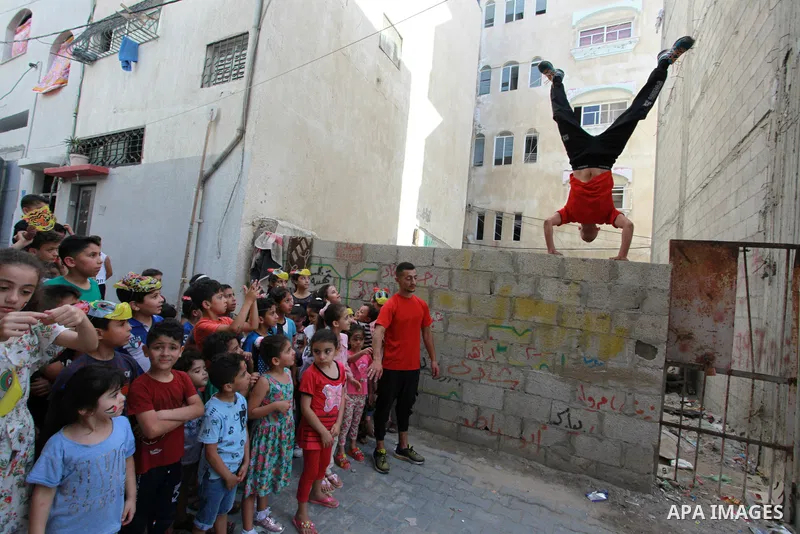 Palestinian volunteers perform acrobatic show in front of children during a mental health support session in Gaza city on June 9, 2021. As Gaza tries to recover from the deadly 11-day Israeli attack, mothers and mental h...