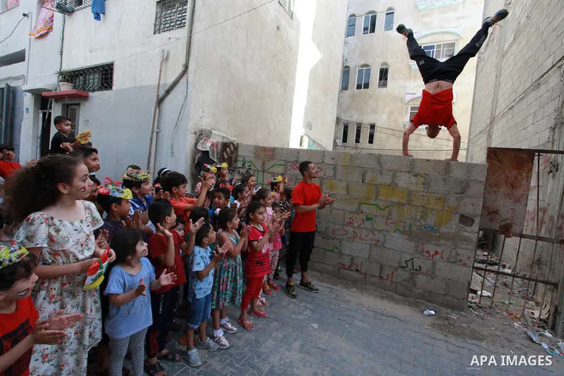 Palestinian volunteers perform acrobatic show in front of children during a mental health support session in Gaza city on June 9, 2021. As Gaza tries to recover from the deadly 11-day Israeli attack, mothers and mental h...