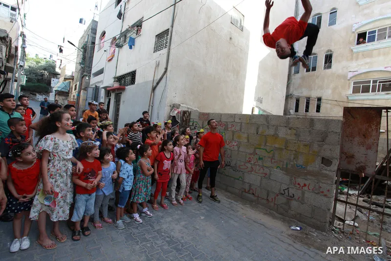 Palestinian volunteers perform acrobatic show in front of children during a mental health support session in Gaza city on June 9, 2021. As Gaza tries to recover from the deadly 11-day Israeli attack, mothers and mental h...