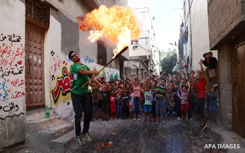 Palestinian volunteers perform acrobatic show in front of children during a mental health support session in Gaza city on June 9, 2021. As Gaza tries to recover from the deadly 11-day Israeli attack, mothers and mental h...