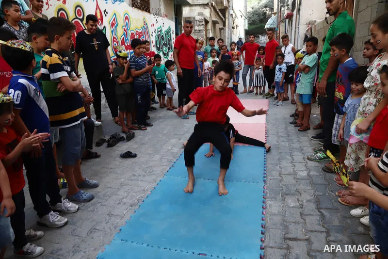Palestinian volunteers perform acrobatic show in front of children during a mental health support session in Gaza city on June 9, 2021. As Gaza tries to recover from the deadly 11-day Israeli attack, mothers and mental h...