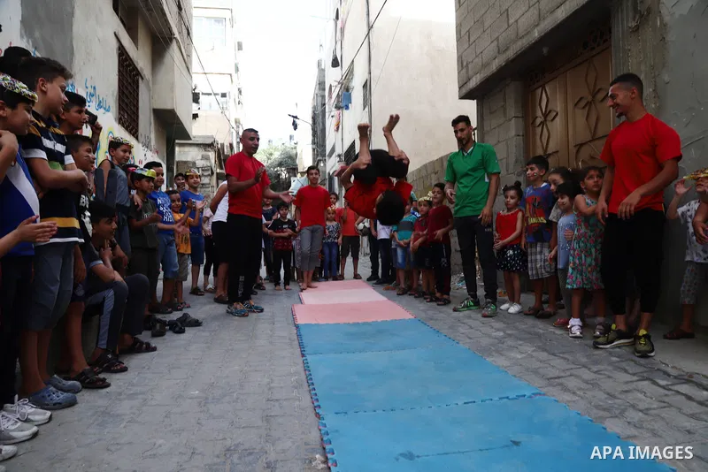 Palestinian volunteers perform acrobatic show in front of children during a mental health support session in Gaza city on June 9, 2021. As Gaza tries to recover from the deadly 11-day Israeli attack, mothers and mental h...