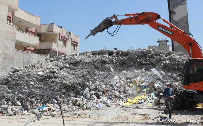 Palestinian workers and bulldozers remove the rubble of buildings destroyed by Israeli air strikes last month, in Gaza city on June 9, 2021. Gaza’s housing ministry said on Thursday that 16,800 housing units had been dam...