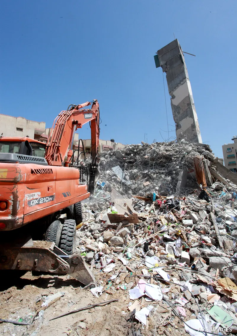 Palestinian workers and bulldozers remove the rubble of buildings destroyed by Israeli air strikes last month, in Gaza city on June 9, 2021. Gaza’s housing ministry said on Thursday that 16,800 housing units had been dam...