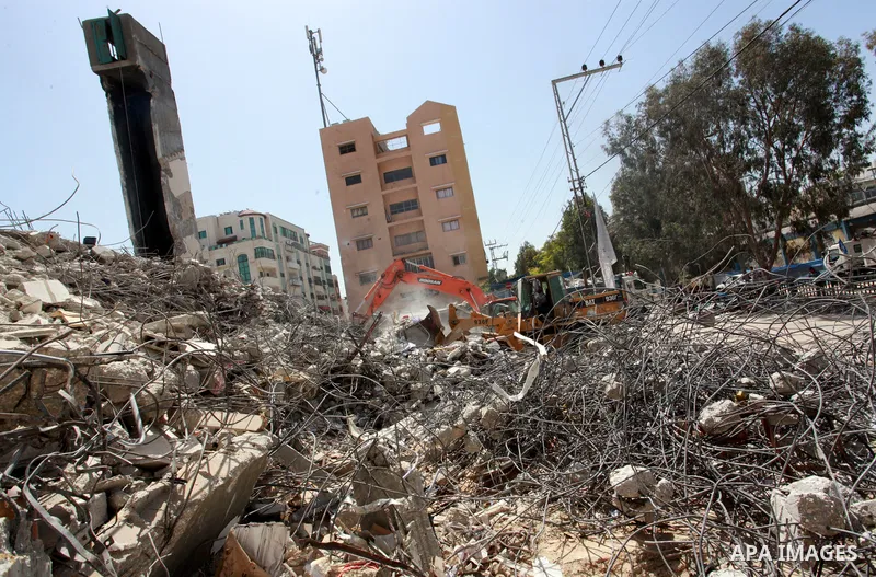Palestinian workers and bulldozers remove the rubble of buildings destroyed by Israeli air strikes last month, in Gaza city on June 9, 2021. Gaza’s housing ministry said on Thursday that 16,800 housing units had been dam...
