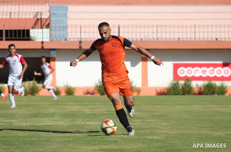 Palestinian football players of Al-Jala' Sports (Orange) and Gaza Sports (white) compete during match of the Al-Quds Ramadan Championship, at Palestine Stadium in Gaza City, on June 6, 2021. Photo by Marihan Al-Khalidi