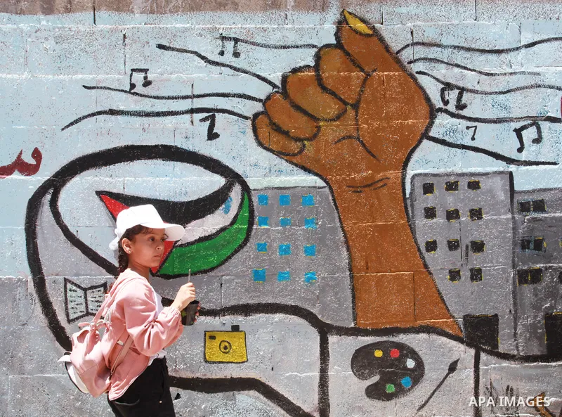 Artists paint wall mural as the Palestinian Artists Association take part in a protest against the destroyed of their headquarters by Israeli air strikes, in front of al-Jawhara tower, in Gaza City on June 6, 2021. Gaza’...