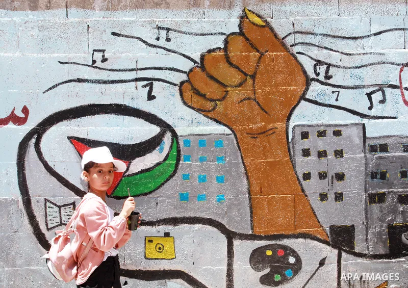 Artists paint wall mural as the Palestinian Artists Association take part in a protest against the destroyed of their headquarters by Israeli air strikes, in front of al-Jawhara tower, in Gaza City on June 6, 2021. Gaza’...