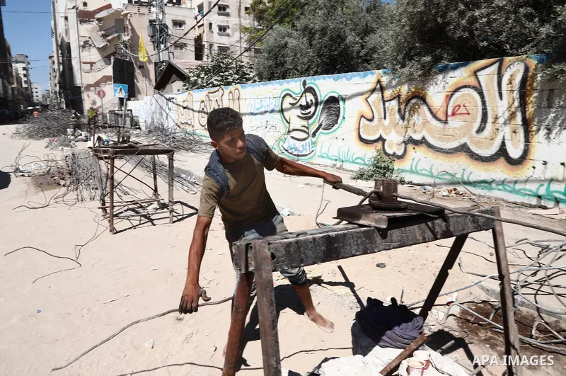 Palestinian workers straighten steel rod as part of the recycling of salvaged construction materials from buildings destroyed during the May 2021 conflict between Hamas and Israel, in Gaza City on June 5, 2021. Gaza’s ho...