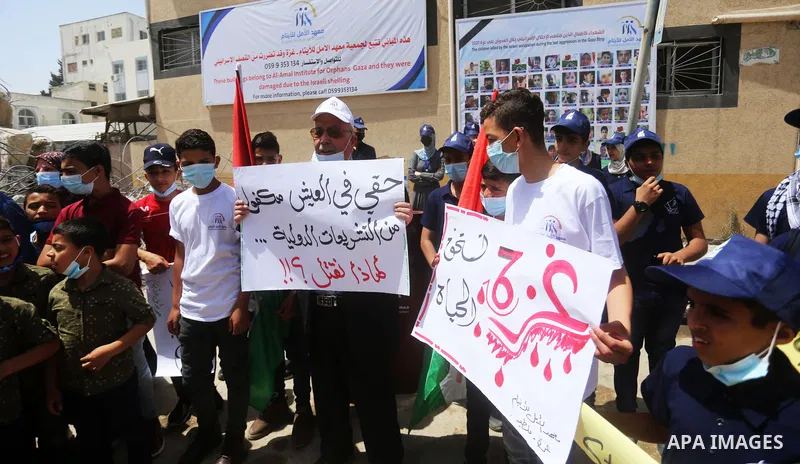 Palestinian children hold placards during a protest against the damaged of buildings belonging to the Al-Amal Institute for Orphans by the Israeli air strikes last month in Gaza city, on June 01, 2021. As Gaza tries to r...