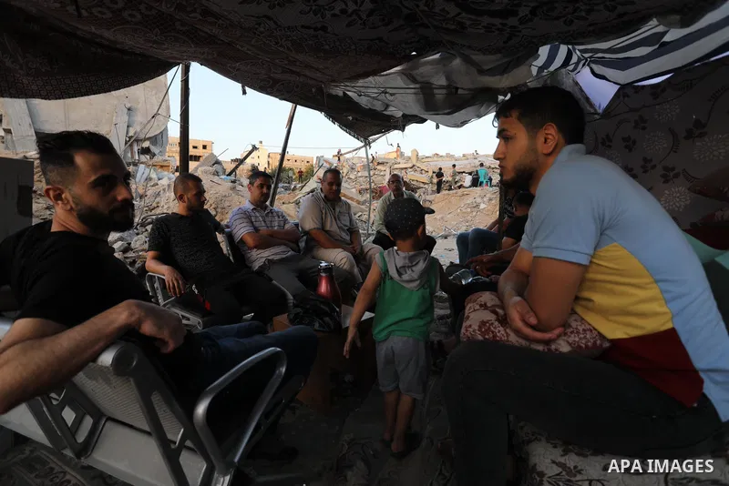 Palestinians sit in a tent that has been set up on top of the ruins of a building destroyed in recent Israeli air strikes, in Beit Lahia in the northern of Gaza strip, on May 25. 2021. Gaza’s housing ministry said on Thu...