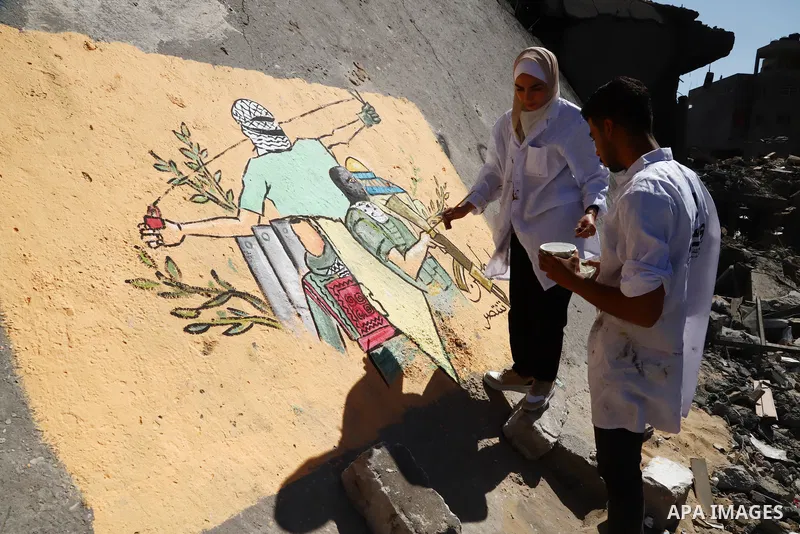 Palestinian artists paint wall mural on the rubble of shorouq tower which was destroyed by Israeli air strike earlier this month, in Gaza City on May 25, 2021. A ceasefire was reached late last week after 11 days of dead...