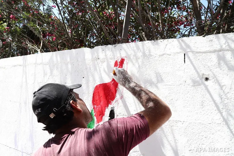 Palestinian artists paint wall mural in front of al-Jawhara tower which was hit by Israeli air strike earlier this month, in Gaza City on May 26, 2021. A ceasefire was reached late last week after 11 days of deadly viole...