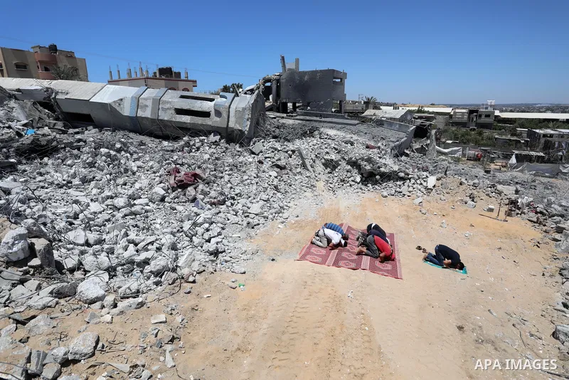 Palestinian Muslim worshippers pray near the rubble of a mosque which was destroyed by Israeli air strikes in Beit Lahia, in the northern Gaza Strip on May 27, 2021. A ceasefire was reached late last week after 11 days o...