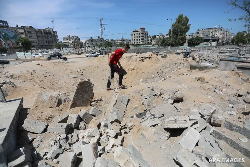 Palestinians inspect the damage around tombs in the old Shujaiya cemetery in Gaza City on May 30, 2021, after recent Israeli bombings. A ceasefire was reached late last week after 11 days of deadly violence between Israe...