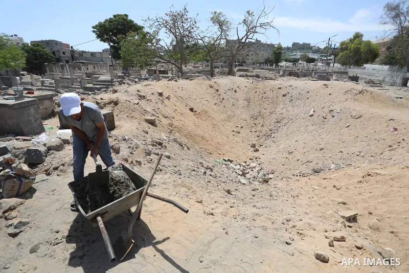 Palestinians inspect the damage around tombs in the old Shujaiya cemetery in Gaza City on May 30, 2021, after recent Israeli bombings. A ceasefire was reached late last week after 11 days of deadly violence between Israe...