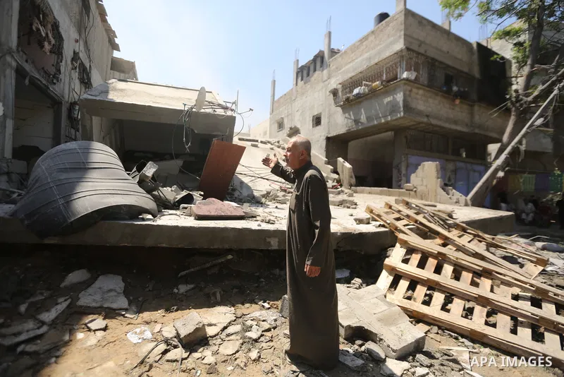 Palestinian gather around the rubble of a residential building in Gaza City, Gaza Strip, May 14, 2021, that was destroyed by an Israeli airstrike. Photo by Bashar Taleb