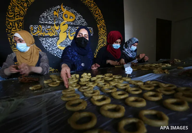 Palestinian deaf girls, wear protective and masks prepare traditional date-filled mini cakes, ahead of Eid al Fitr, at the Hamm Association, in the Maghazi camp, in the center of Gaza strip on May 10, 2021. Eid al-Fitr t...