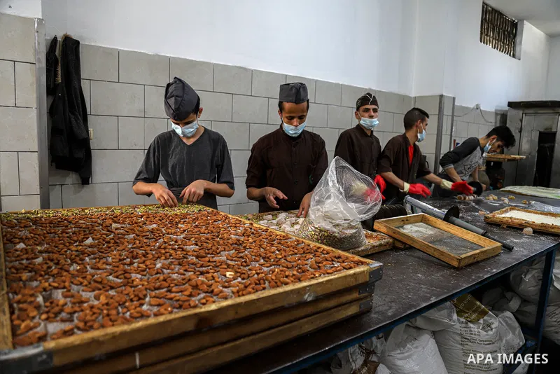 Palestinians prepare sweet known in Arabic as "Halkoum" to be sold ahead of the Eid al-Fitr holiday, at a factory in Gaza City on May 09, 2021. Eid al-Fitr this year is different in light of the COVID-19 pandemic. Eid al...