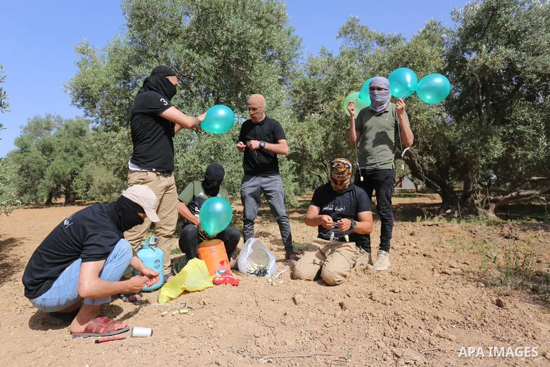 Masked Palestinian followers of the Al-Nasser Salah al-Din Brigades near Al-Bureij camp, in the center of the Gaza Strip, prepare to fly incendiary balloons across the eastern border toward Israel, on May 8, 2021, a day...