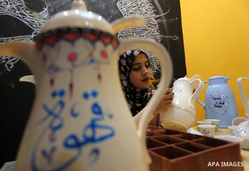 Palestinian artist, Abeer Al-Tallaa, 23, paints on the pots and cups of coffee the congratulatory phrases for Eid Al Fitr, at Maghazi refugee camp in the center of the Gaza Strip, on May 8, 2021. People flock markets and...