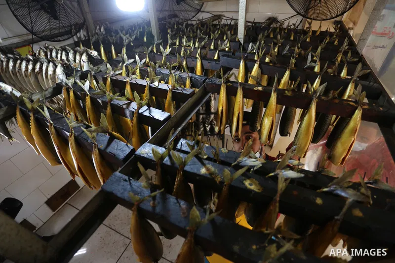 Palestinian men wearing masks, prepare Smoked Herring or, salted fish to be sold in markets days before of Eid al Fitr holiday in Nuseirat in the center of Gaza Strip on May 5, 2021. People flock markets and shopping mal...