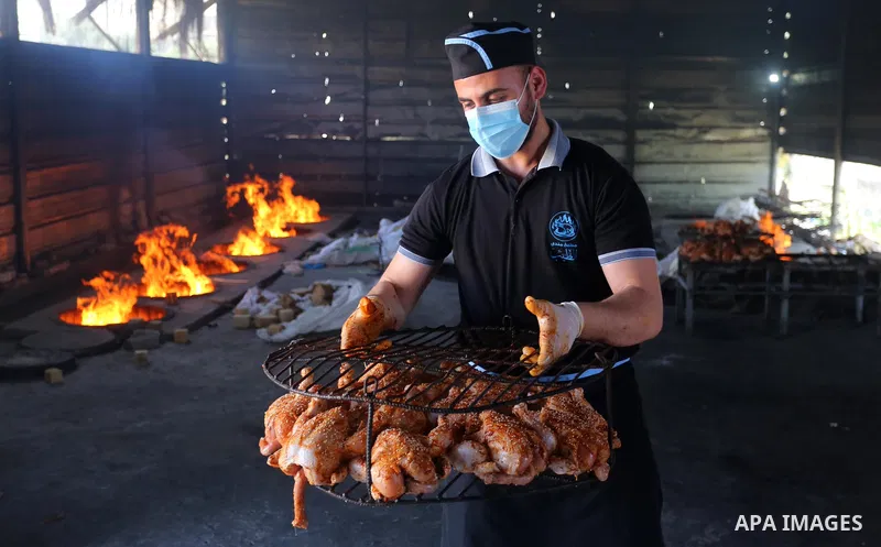 Palestinian chefs cook chickens and rice on firewood by burying them inside a barrel underground, to sell it to customers during the holy month of Ramadan in Deir al-Balah in the center of Gaza Strip, aimd the COVID-19 p...