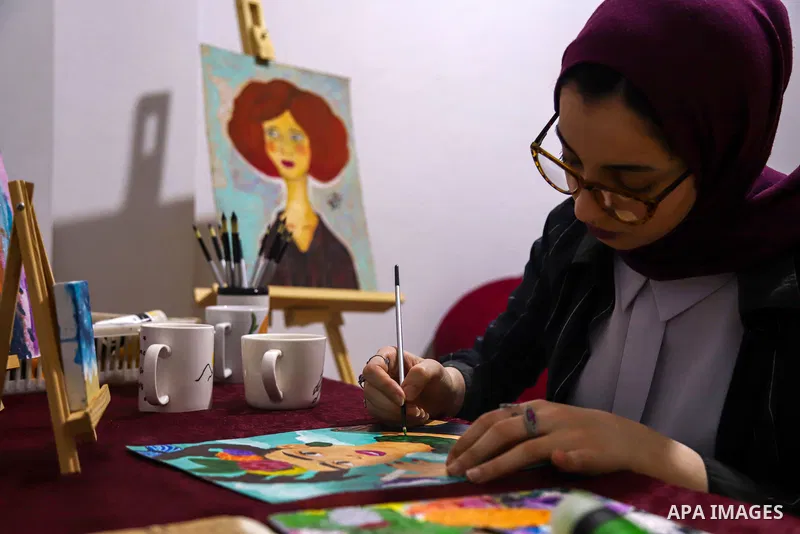 Palestinian artist, Farah Al-Ajl, 20, paints a painting on a papers at her home, in Gaza city on May 4, 2021. Al-Ajl, is studying business administration, where she works in this profession to help herself to complete he...