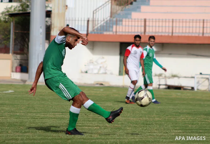 Palestinian football players of Al-Shejaiya Union (green) and Gaza Sports (White) compete during match of the Al-Quds Ramadan Championship, at Palestine Stadium in Gaza City, on April 25, 2021. Photo by Marihan Al-Khalid...