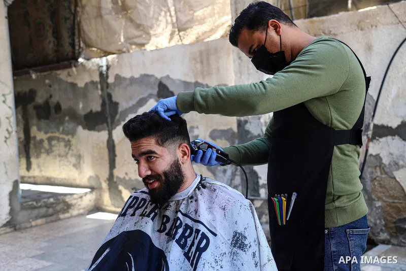 Palestinian barber, Mohammed al-Bouji, 37, wears a mask and gloves, shaves for clients, in the southern Gaza Strip city of Rafah, on April 28, 2021. Al-Bouji launched The delivery shaving services amid the coronavirus di...