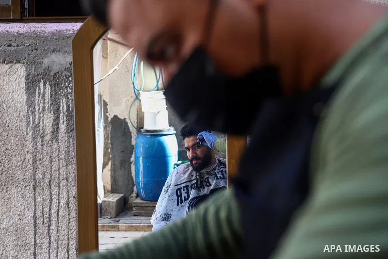 Palestinian barber, Mohammed al-Bouji, 37, wears a mask and gloves, shaves for clients, in the southern Gaza Strip city of Rafah, on April 28, 2021. Al-Bouji launched The delivery shaving services amid the coronavirus di...