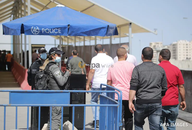 Members of the Israeli security forces stand guard at the Qalandia checkpoint between the West Bank town of Ramallah and Jerusalem, as Palestinians cross to attend the second Friday prayers of the fasting month of Ramada...