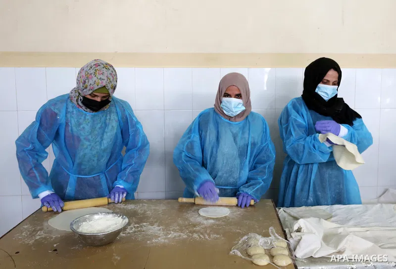 Palestinian women wear protective and maskes prepare traditional food of Couscous "Maftoul", samosa and Kubba in Khan Younis in the southern Gaza Strip, on April 11, 2021 to sell it to customers a head of Islamic holy mo...