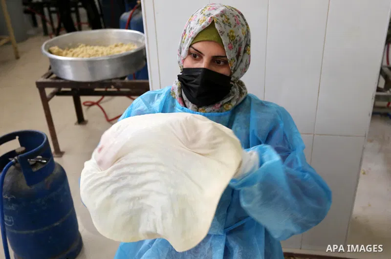 Palestinian women wear protective and maskes prepare traditional food of Couscous "Maftoul", samosa and Kubba in Khan Younis in the southern Gaza Strip, on April 11, 2021 to sell it to customers a head of Islamic holy mo...
