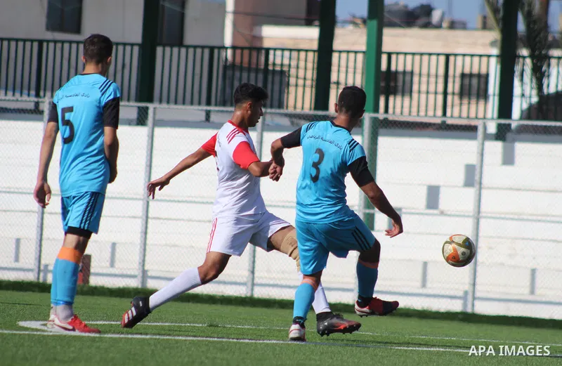Palestinian football players of Gaza Sports club (White) and Al Qadisia club (blue) compete during the first division League, ​at Rafah municipal stadium, in Rafah in the southern of Gaza Strip on March 30, 2021. Photo b...