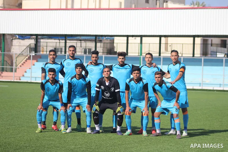 Palestinian football players of Gaza Sports club (White) and Al Qadisia club (blue) compete during the first division League, ​at Rafah municipal stadium, in Rafah in the southern of Gaza Strip on March 30, 2021. Photo b...