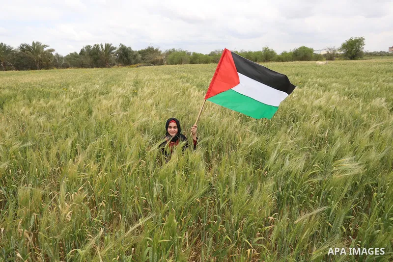 Palestinians carry the Palestinian flag near the border with Israel, in Khan Younis in the southern of Gaza Strip, on March 30, 2021. Palestinians every year mark Land Day on March 30 commemorating the six Palestinians s...
