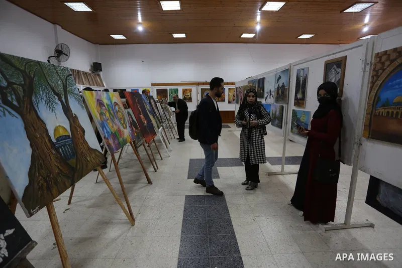 Palestinians attend the first international exhibition in Palestine for plastic art entitled (Palestine is a land and a people), inside the YMCA in Gaza City on March 29, 2021. Contemporary Palestinian art finds its root...
