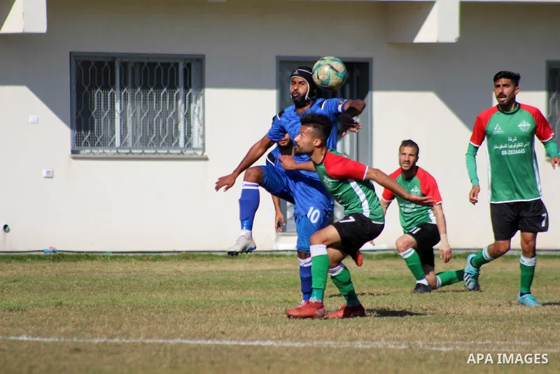Palestinian football players of Shabab Jabalia (blue) and Khadamat Rafah club (green) compete during match premier League in Beit Lahia Stadium, in Beit Lahia in the northern Gaza Strip on March 28, 2021. Photo by Mariha...