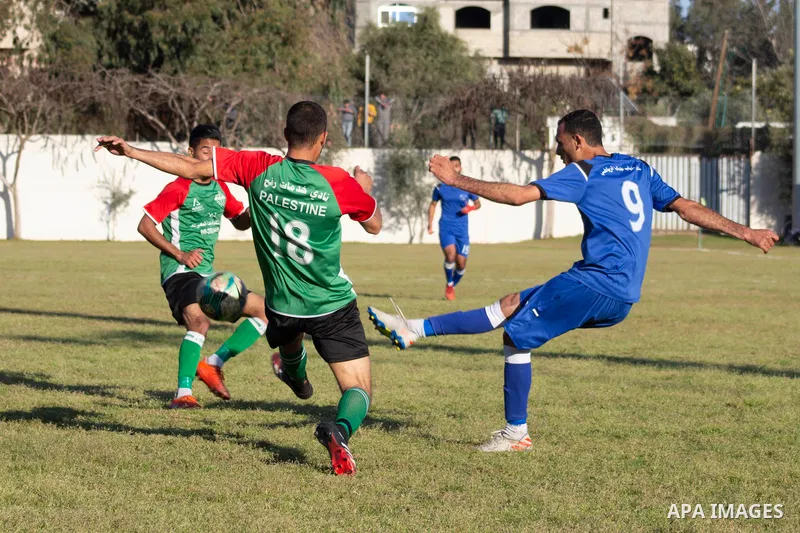 Palestinian football players of Shabab Jabalia (blue) and Khadamat Rafah club (green) compete during match premier League in Beit Lahia Stadium, in Beit Lahia in the northern Gaza Strip on March 28, 2021. Photo by Mariha...