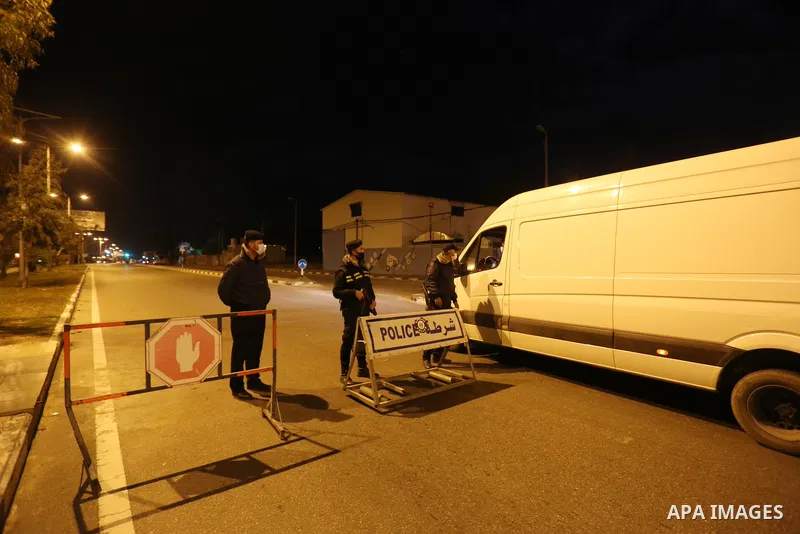 Palestinian policemen wear face masks, guard a barrier blocking a road, in Deir Al-Balah in the center of the Gaza Strip, on March 27, 2021, after the Ministry of Interior in Gaza City announced the full lockdown on Satu...