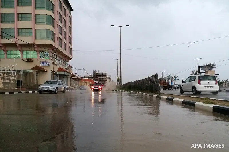 Palestinians walk in a street during a rainy day, in Gaza city, on March 26, 2021. Weather today is partly cloudy to cloudy and relatively cold to cold with a drop in temperature, which remains unseasonably low, accordin...