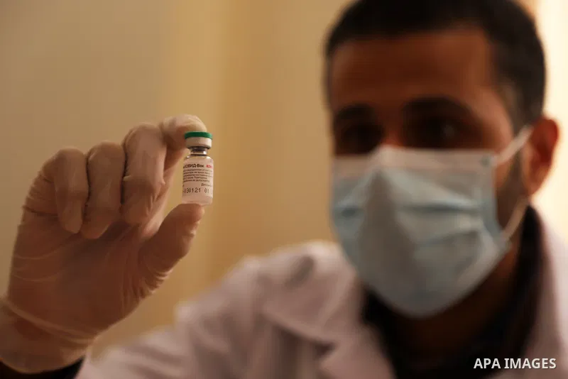 A health worker holds a vial of vaccine as he prepares to vaccinate a Palestinian man against the coronavirus at the UNRWA clininc, in Gaza city on March 25, 2021. The Palestinian authorities have begun administering vac...
